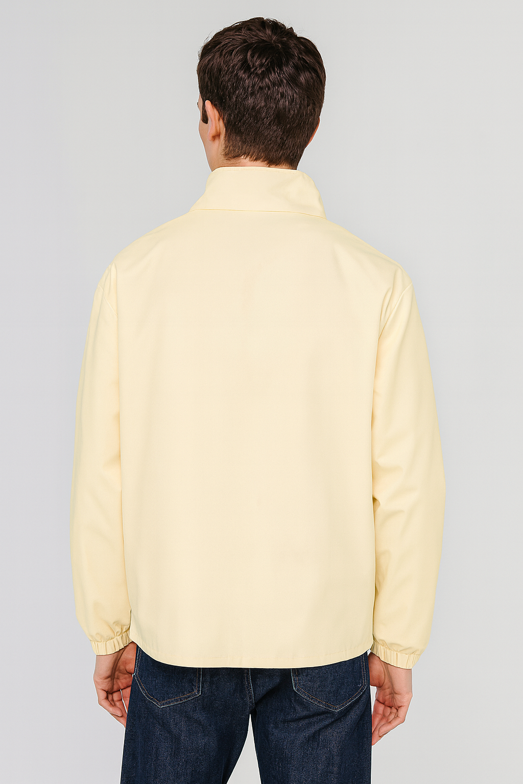 Rear view of cream men’s stand collar jacket with clean straight hem and tailored fit.