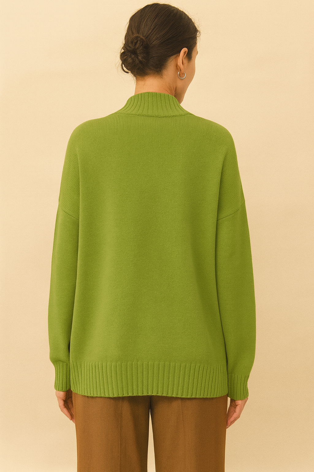 Back view of emerald green Nordash Oversized Turtleneck Sweater, ribbed collar and cuffs, paired with tailored trousers in softly lit studio.
