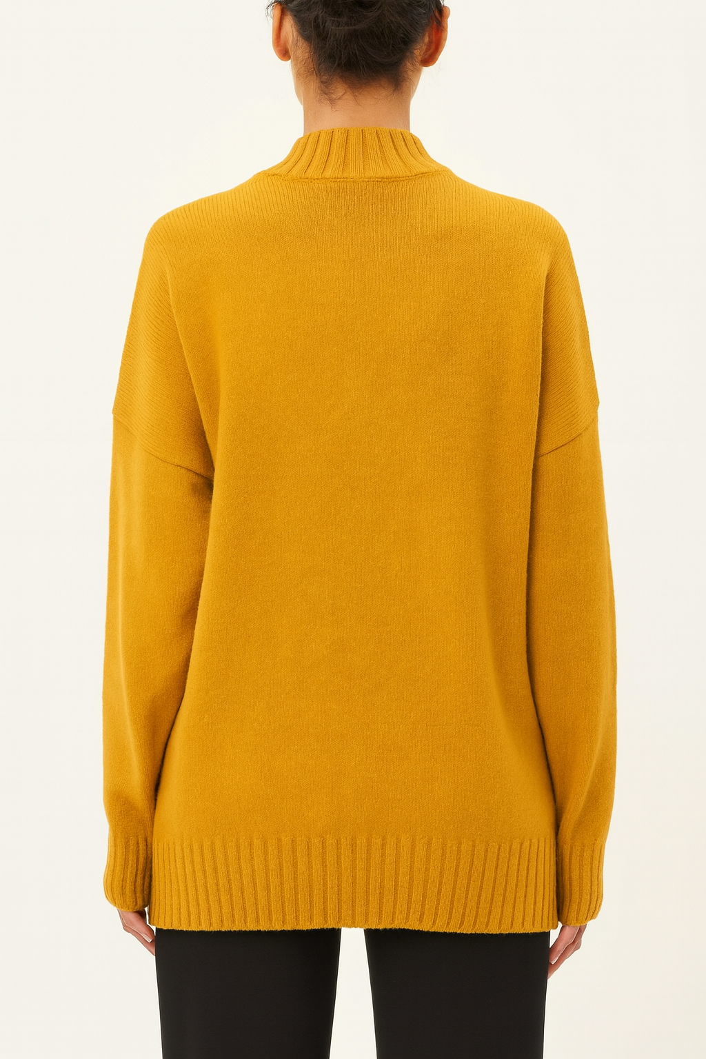 Back view of mustard yellow Nordash Oversized Turtleneck Sweater, oversized fit with ribbed cuffs and hem, styled with dark trousers on beige background.
